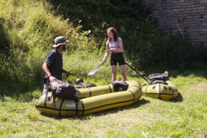Packraft rental experience in Müllerthal, Luxembourg – a packrafter paddling through a scenic forest river, surrounded by towering rock formations and lush greenery